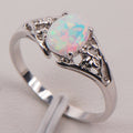 Silver ring with a colorful opal stone on a light gray background