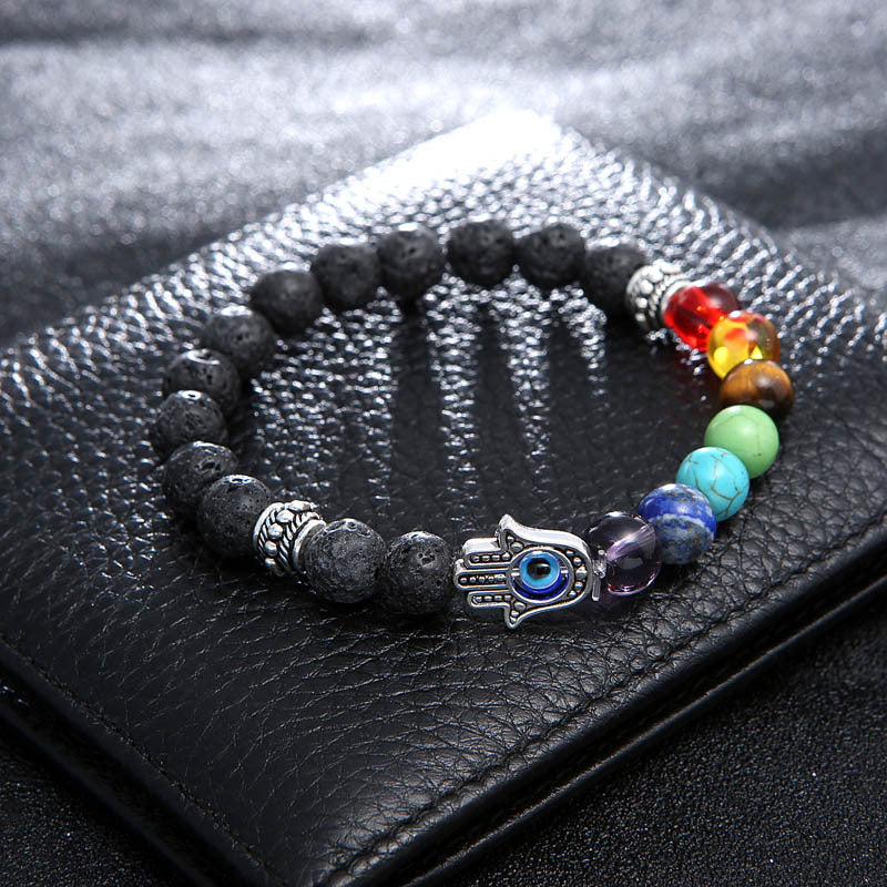 Multicolored beaded bracelet with a Hamsa hand charm on a black leather surface