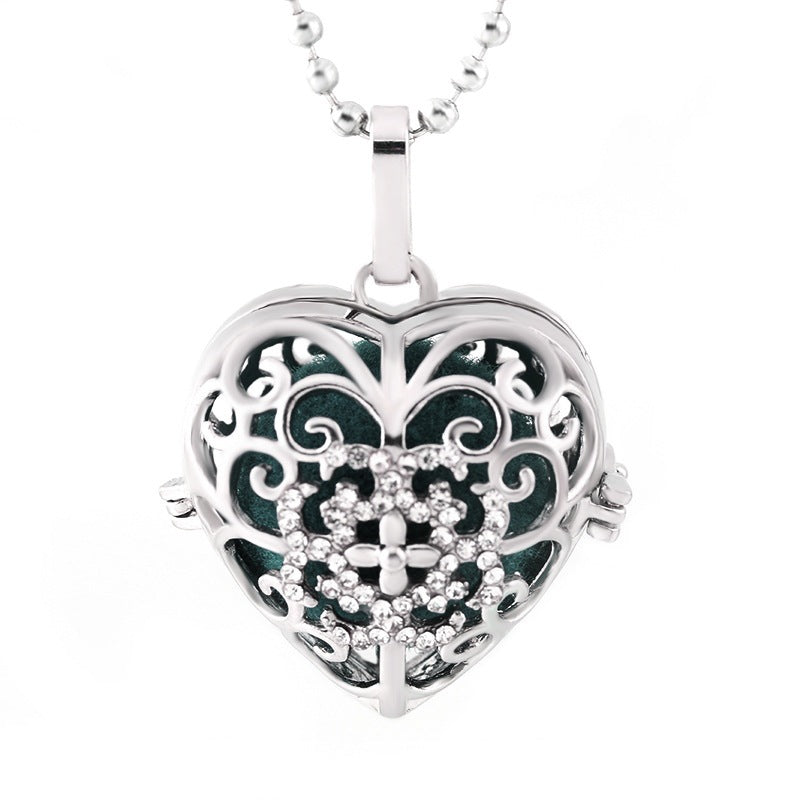 Heart-shaped silver pendant with intricate designs on a white background