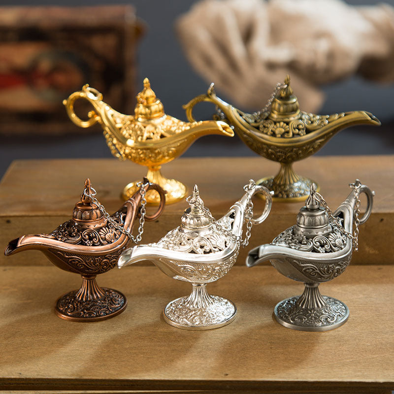 Decorative Aladdin lamps in gold, silver, and bronze on a wooden surface.
