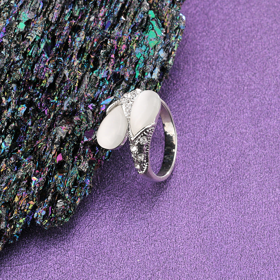 Silver ring with white stone on a textured purple surface