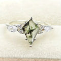 Ring with a green gemstone and clear stones on a white background