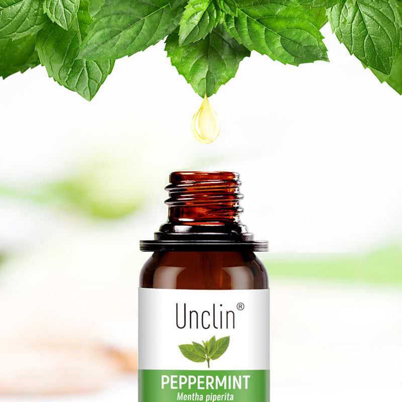 Bottle of Unclin peppermint essential oil with a droplet and mint leaves on a white background