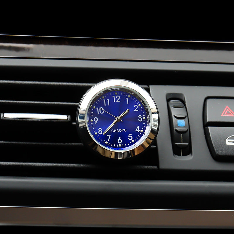 Car clock with blue face and silver frame on a car's air vent.