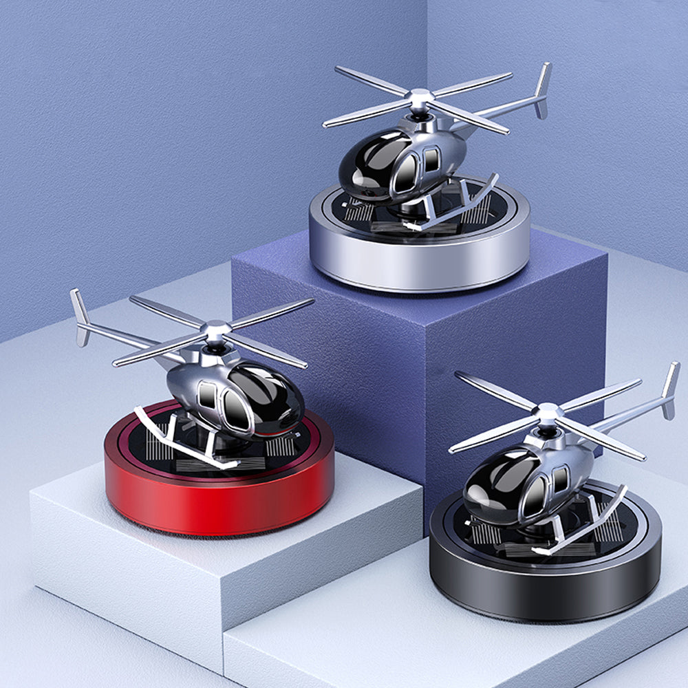 Three miniature helicopters on stands with different color bases against a light blue background