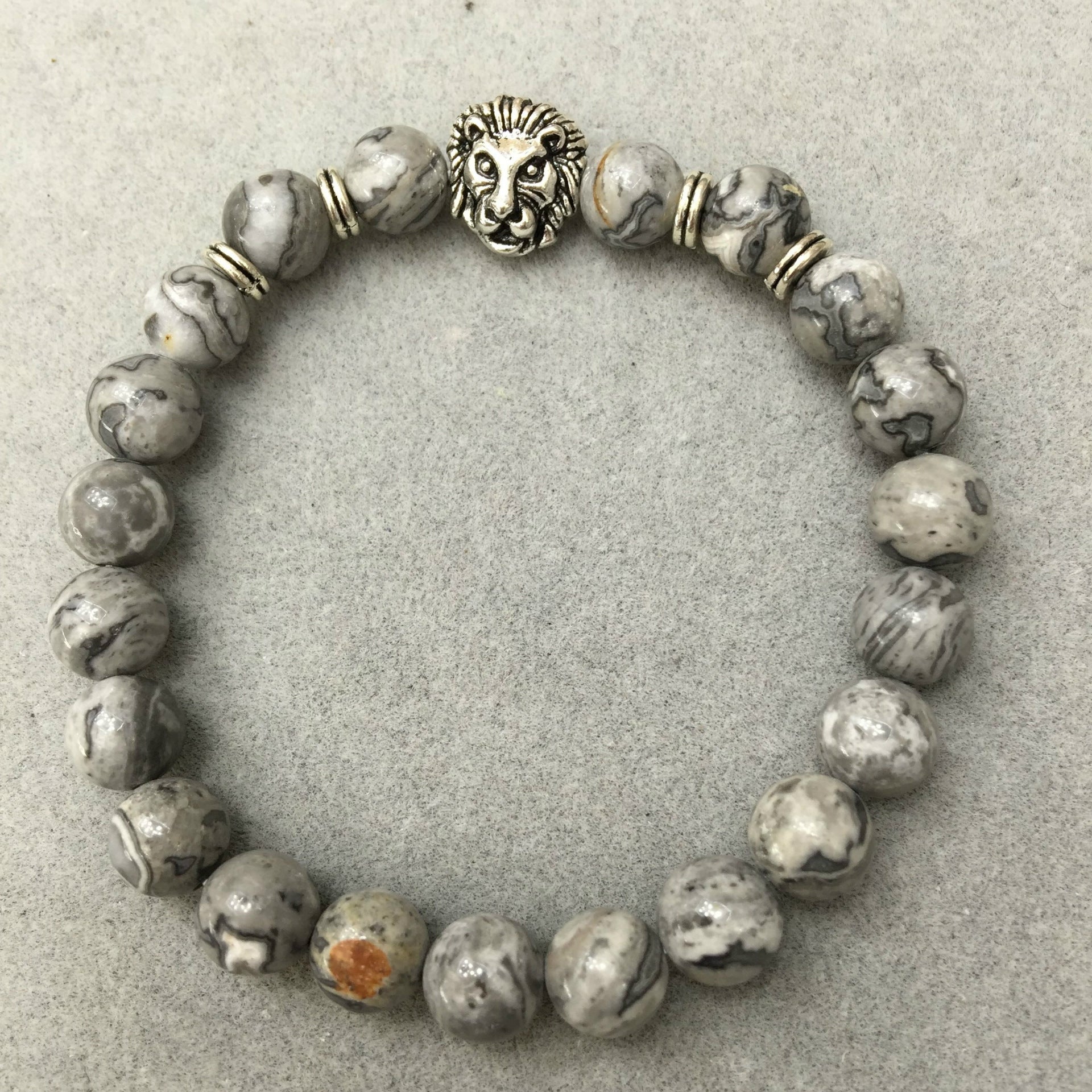 Beaded bracelet with lion head charm on a gray background