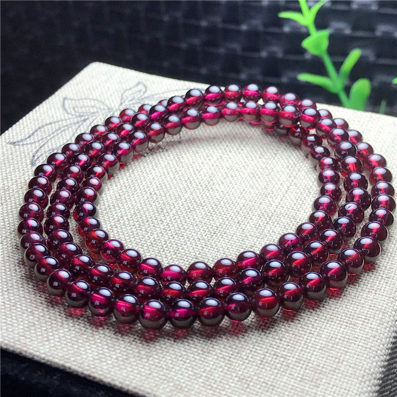 Beaded bracelet with red gemstones on a textured surface