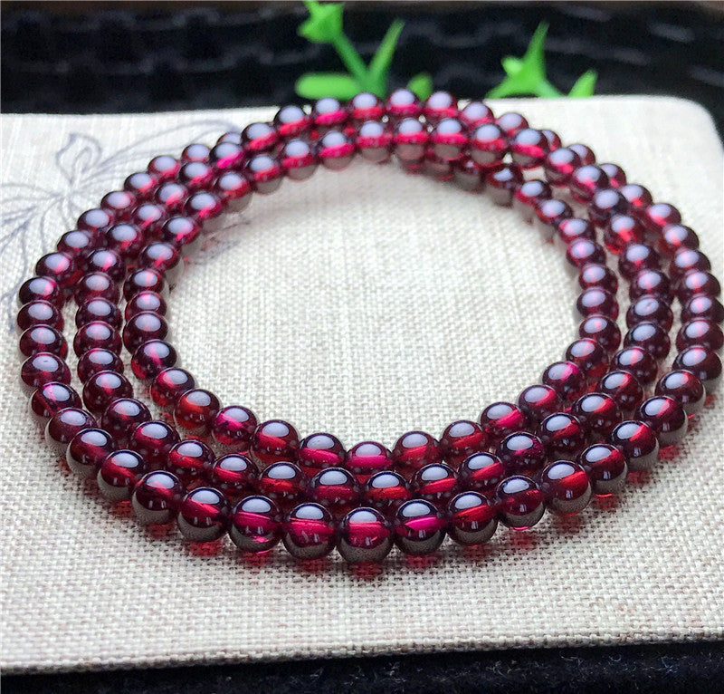 Beaded bracelet with red gemstones on a white fabric background