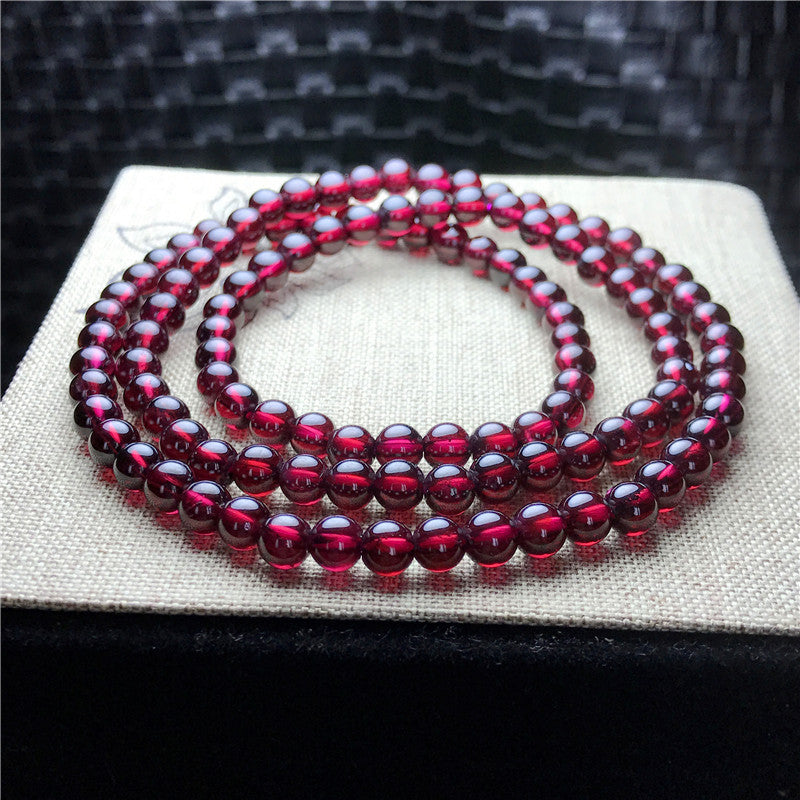 Red beaded necklace on a white surface with a dark textured background