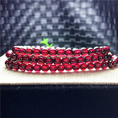 Stack of red beaded bracelets on a textured surface with a blurred background