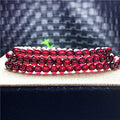 Stack of red beaded bracelets on a textured surface with a blurred background