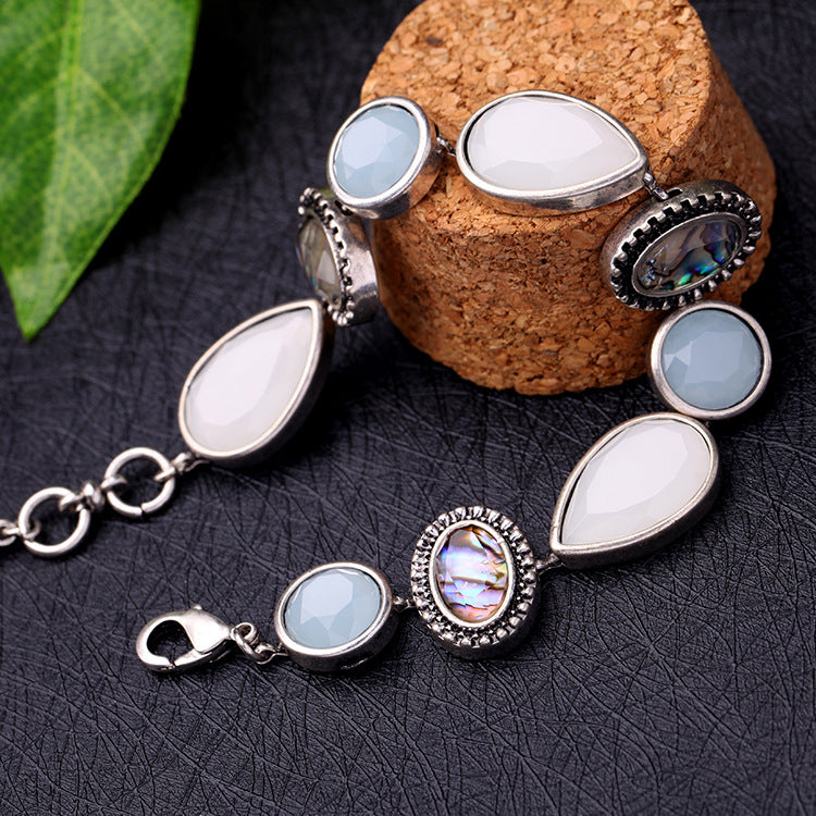 Silver bracelet with teardrop-shaped gemstones on a dark surface