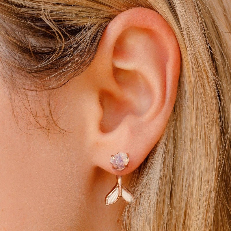Close-up of an ear wearing a pink gemstone earring with a matching gold bar.