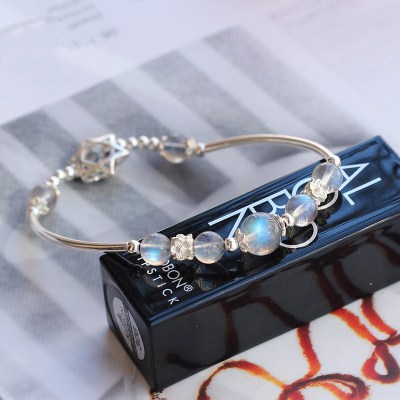 Silver bracelet with beads on a black lipstick case with visible branding.