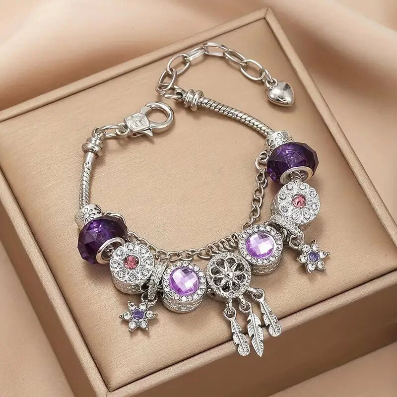 Silver bracelet with purple and pink charms on a beige box