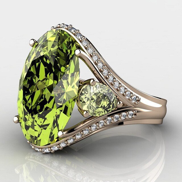 Gold ring with green gemstone and small diamonds on a reflective surface