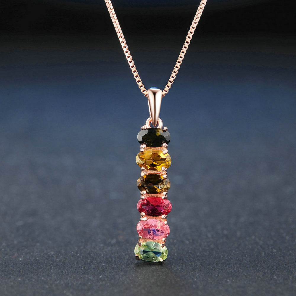 Multicolored gemstone pendant on a chain against a dark background