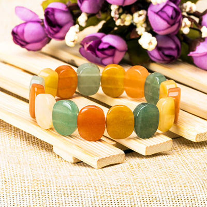Colorful beaded bracelet on a wooden stand with flowers in the background