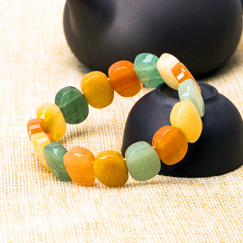 Colorful beaded bracelet on a black stone with a textured beige background