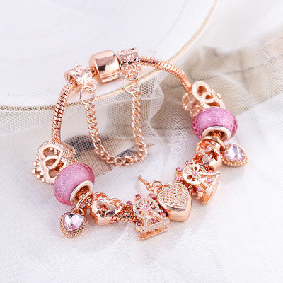 Rose gold charm bracelet with pink beads on a white background