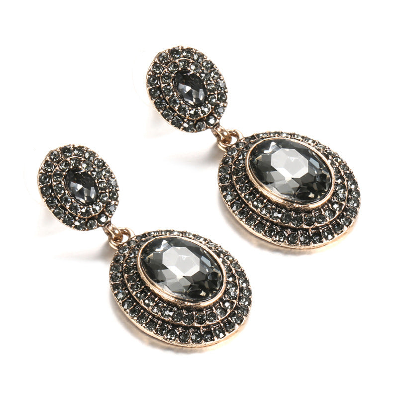 Pair of ornate earrings with dark gemstones on a white background
