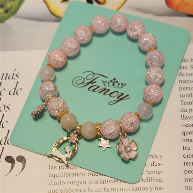 Pink beaded bracelet with charms on a 'Fancy' branded card