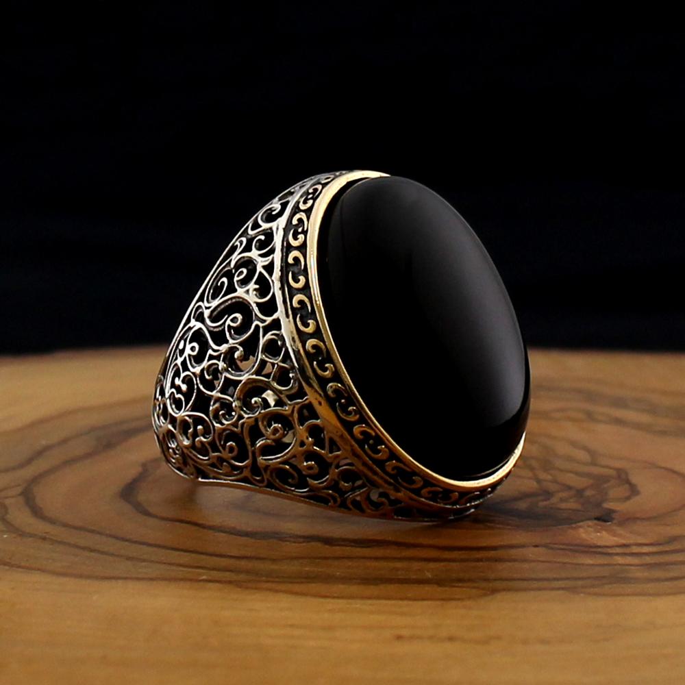 Decorative ring with black stone and gold filigree on a wooden surface