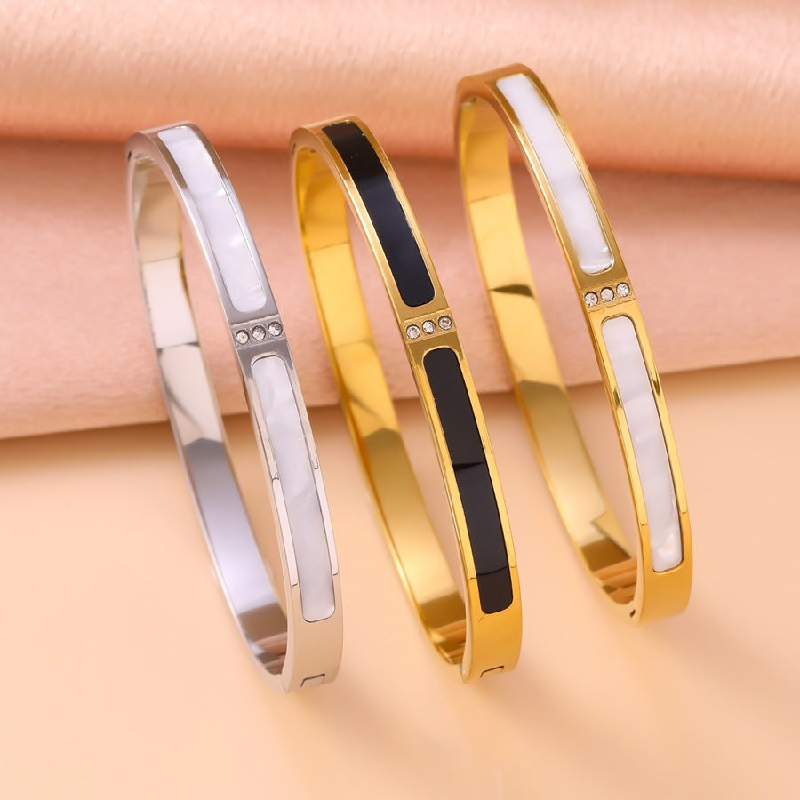 Three gold and silver bracelets with black accents on a beige background
