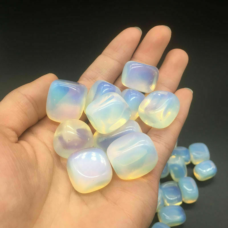 Hand holding a collection of iridescent stones against a dark background