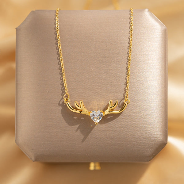 Gold necklace with heart-shaped pendant on a beige box against a gold background