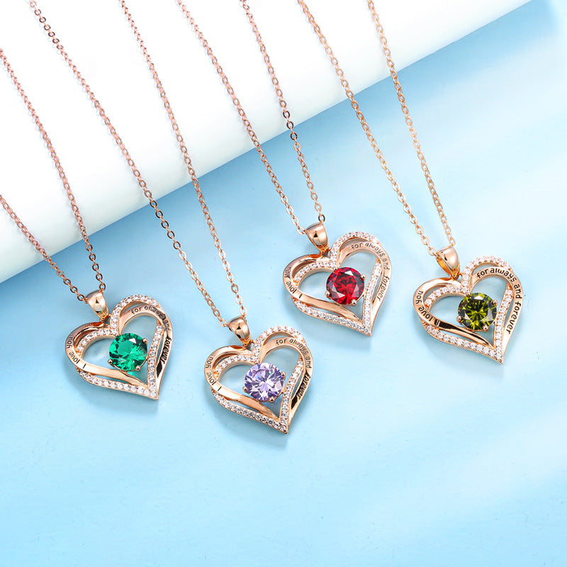 Heart-shaped pendants with colored gemstones on rose gold chains against a light blue background
