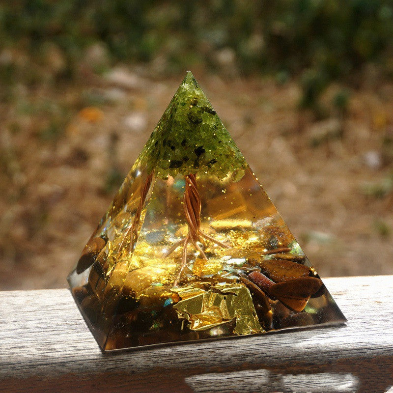Pyramid-shaped crystal with embedded leaves on a wooden surface