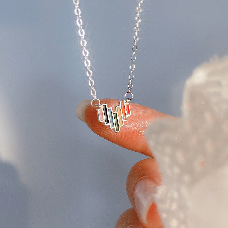 Necklace with a colorful pendant held by a hand against a blurred background