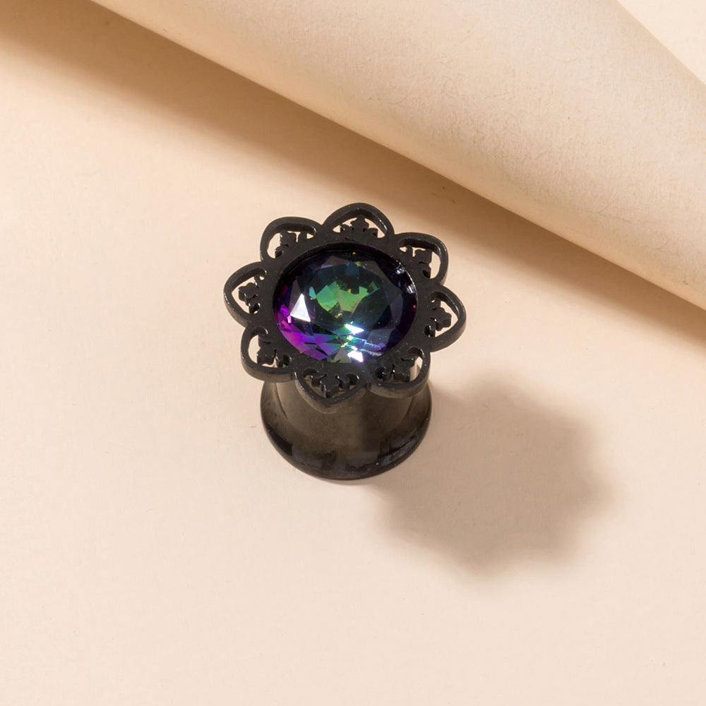Black lace-style earring with a colorful gemstone on a beige background