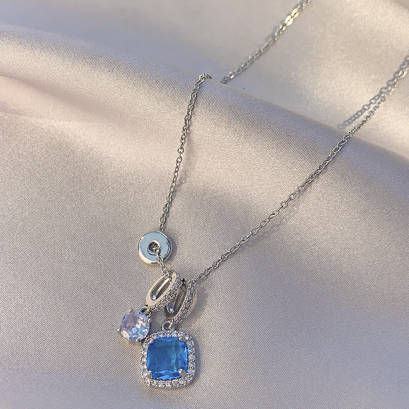 Silver necklace with a blue gemstone pendant on a light fabric background
