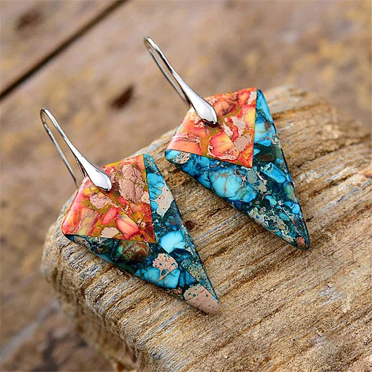 Colorful triangle-shaped earrings on a wooden surface
