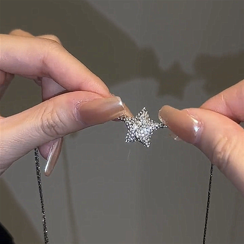 Star-shaped earring held between fingers against a neutral background