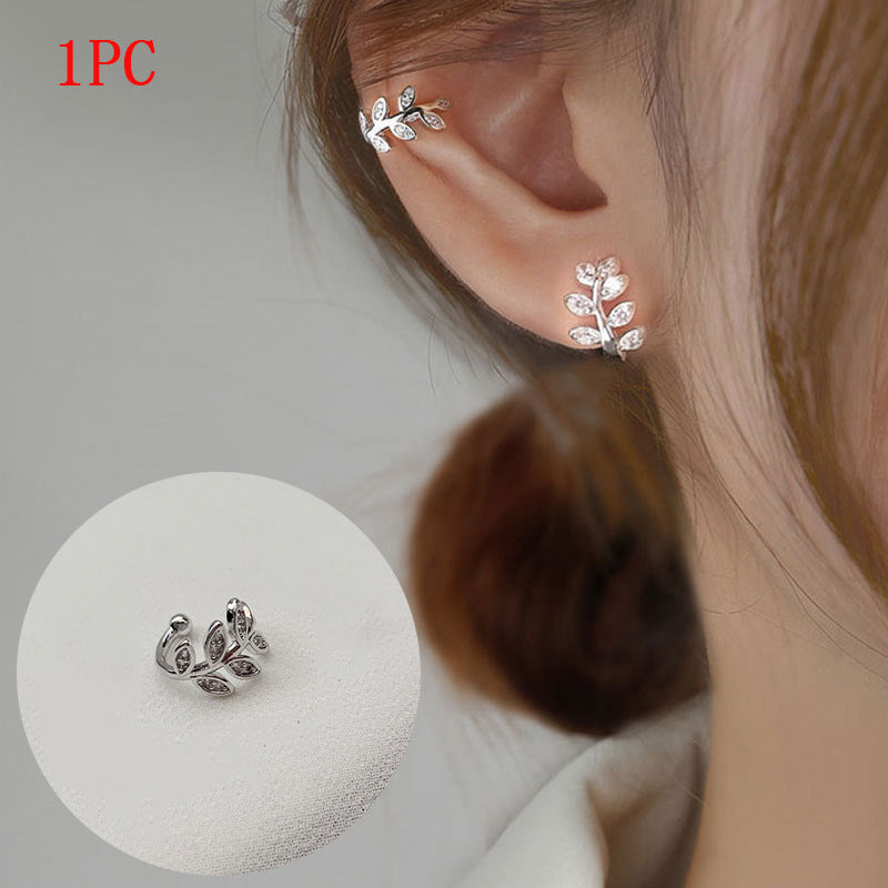 Silver leaf-shaped earrings worn on an ear with a close-up inset of the earring.