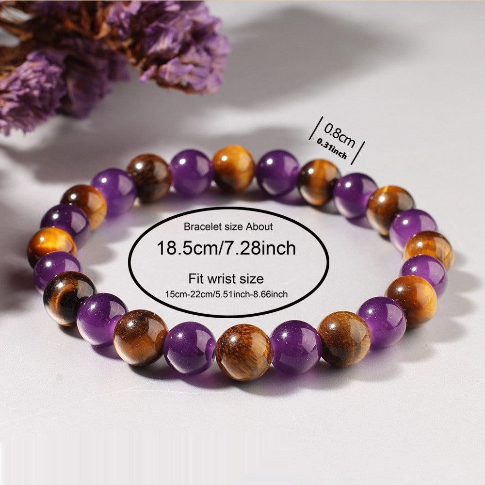 Multicolored beaded bracelet on a white surface with purple flowers in the background