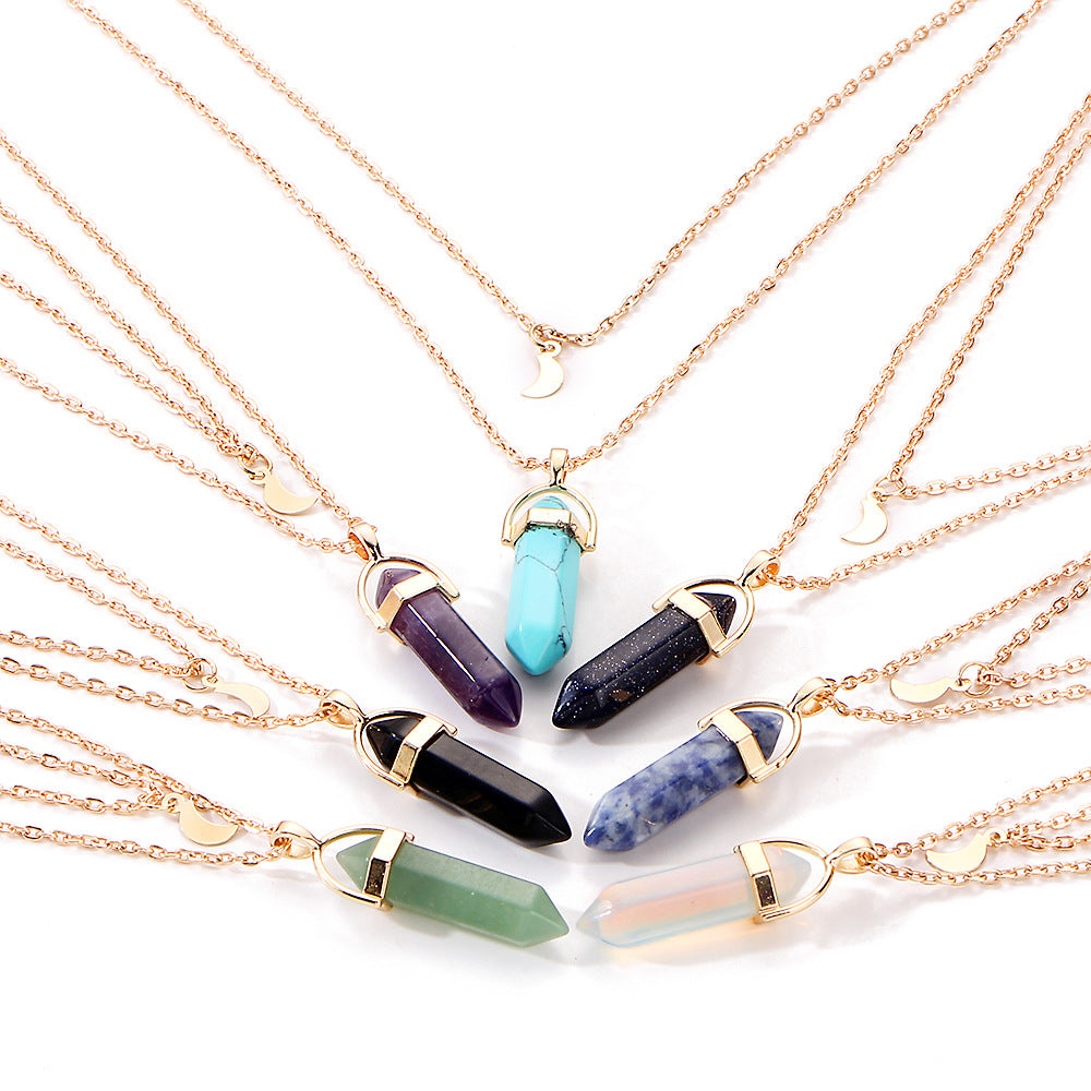 Necklaces with crystal pendants on gold chains against a white background