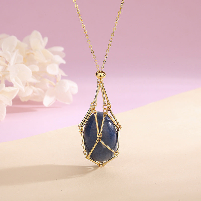 Gold necklace with a blue stone pendant on a pink background
