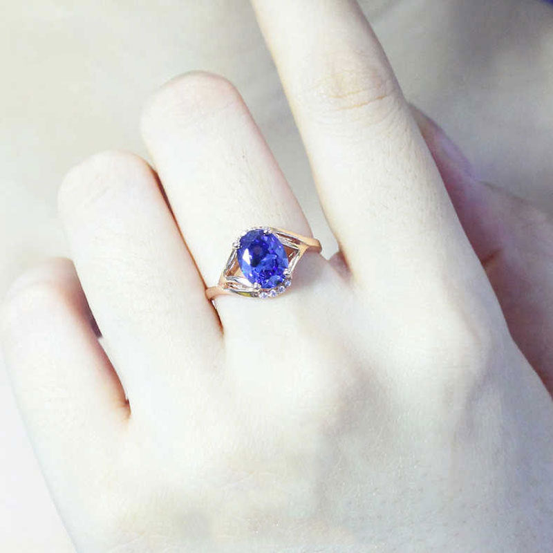Ring with a blue gemstone on a hand against a white background