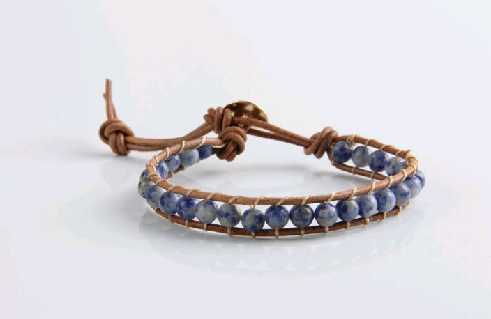 Bracelet with blue beads and brown leather strap on a white background