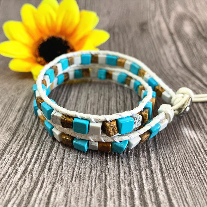 Multicolored beaded bracelet on a wooden surface with a sunflower in the background