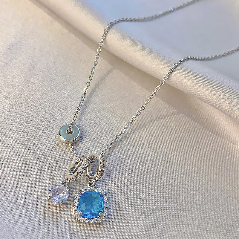 Necklace with blue gemstone pendant on a light fabric background