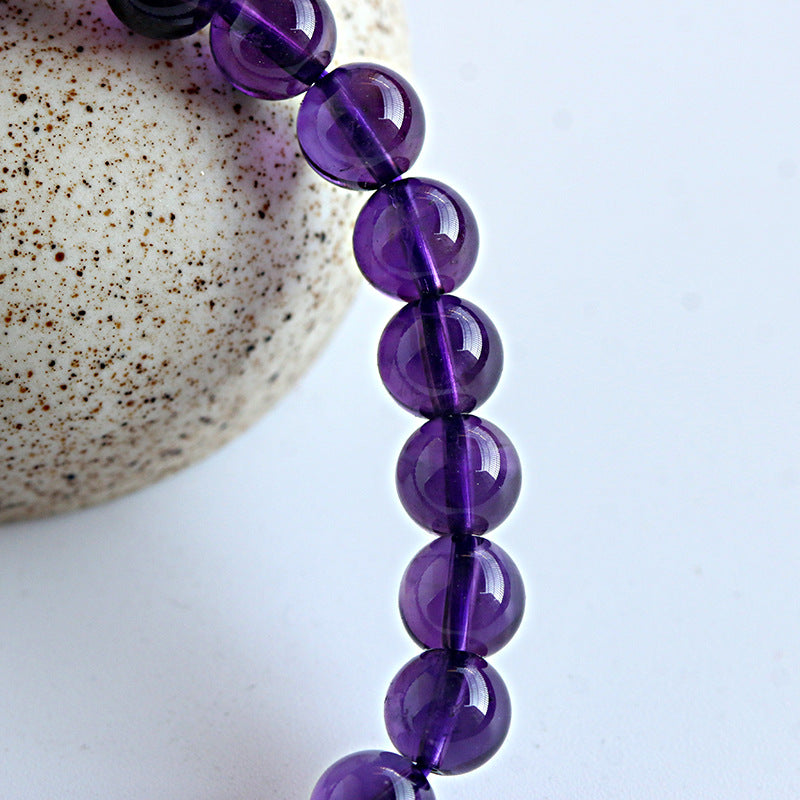 Purple beaded bracelet on a speckled stone surface