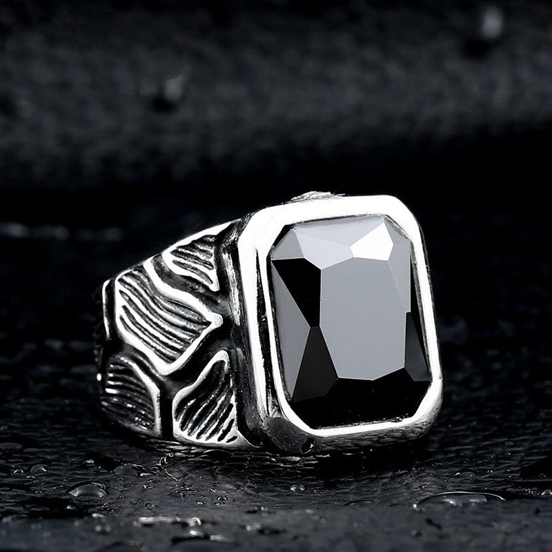 Silver ring with a black stone on a dark textured background