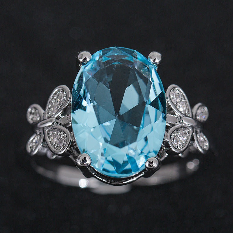 Ring with a large blue gemstone and silver accents on a dark background