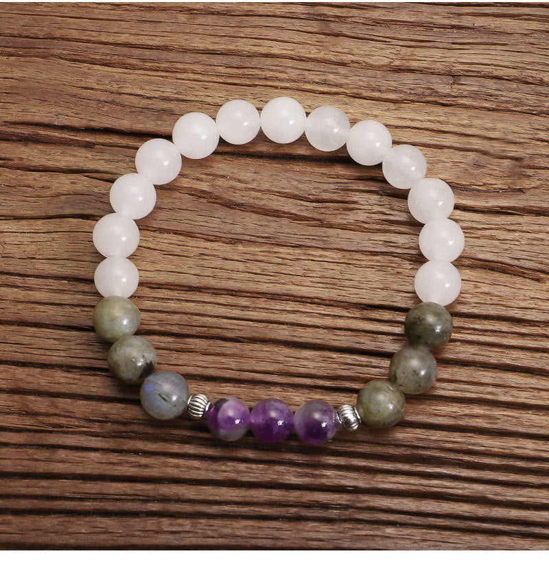 Beaded bracelet with white, green, and purple beads on a wooden surface