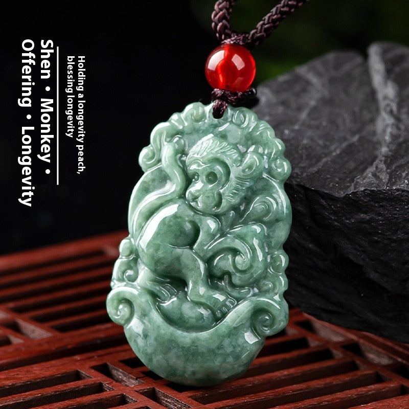 Green jade monkey pendant with red bead on a dark background